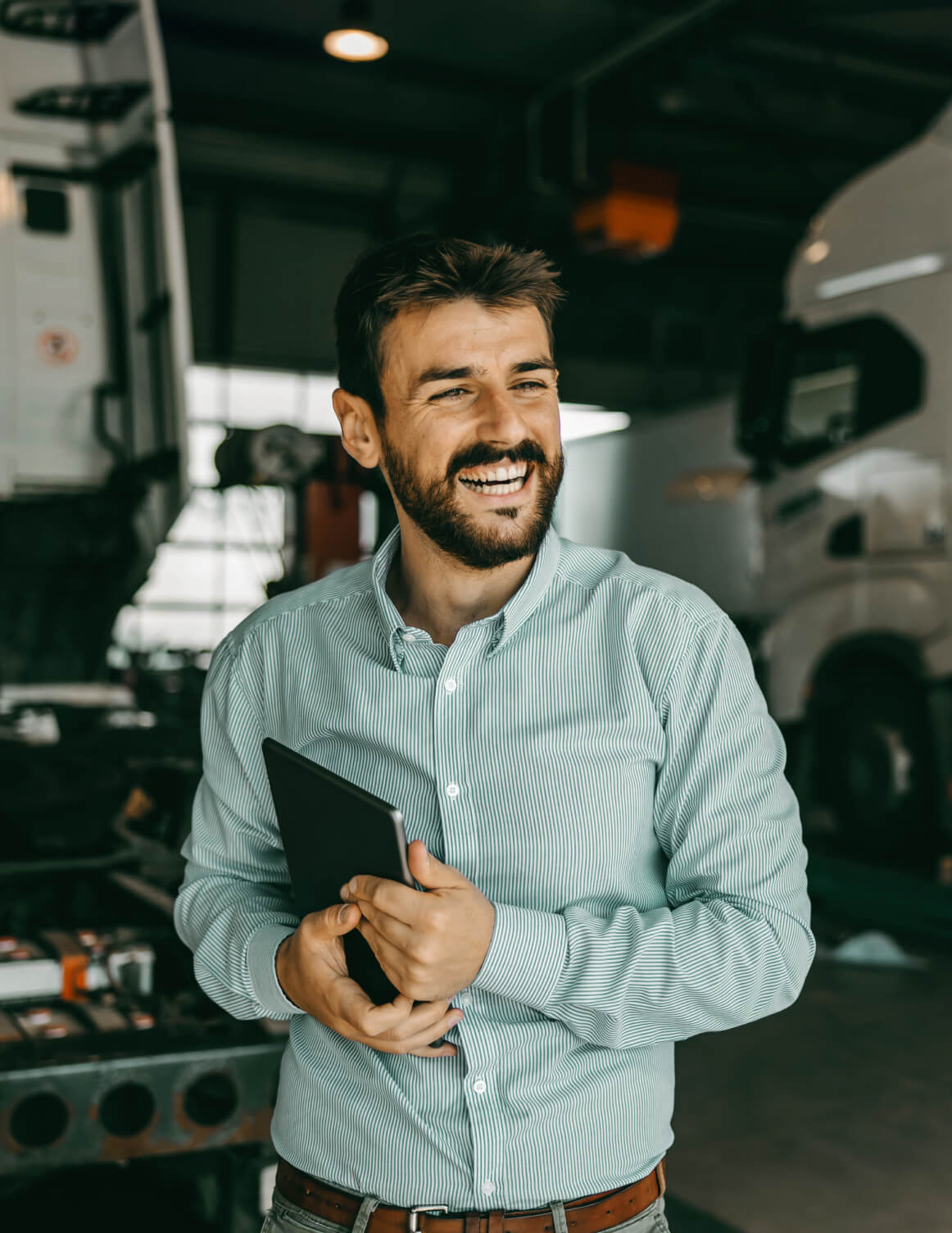person smiling and holding an ipad in a vehicle hanger